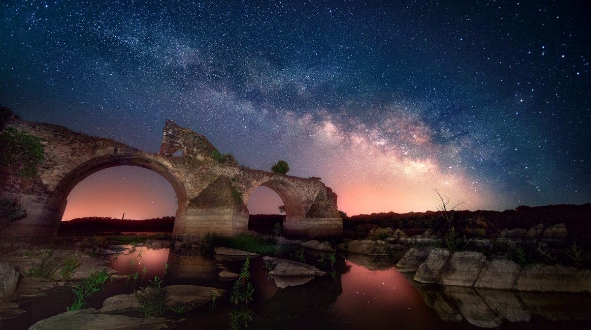 Long exposure night photography showing the Milky Way above the ancient bridge of Ajuda in Elvas, Portugal, near the border with Spain